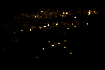 Golden blurred bokeh lights on black background. Glitter sparkle stars for celebrate. Overlay for...