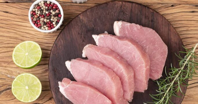 Sliced raw pork loin meat over wooden board with seasonings