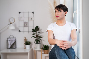 The man is wearing makeup. Transgender posing in the studio.