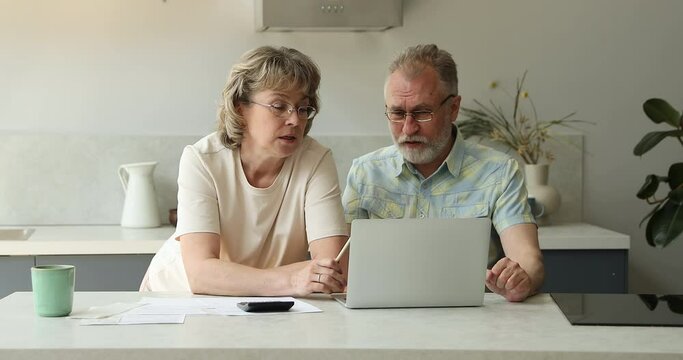Worried aged wife comfort angry elderly husband sit by laptop deal with financial difficulties when paying bills invoices. Annoyed distressed retired couple check bank account see overspending budget