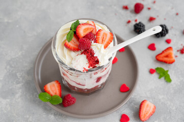 Red Velvet cake trifle with fresh berries in a glass jar on a gray concrete background. Dessert for Valentine's Day. Copy space.