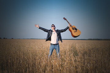 A man singer with the guitar outdoors.