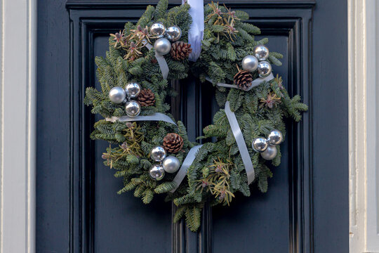 Season Greeting Theme, Christmas Wreath Made From Green Pine Tree Assortment Of Flowers Hanging On Front Door, Xmas Ring Decoration With Colourful Balls And Stars On Wooden Background.