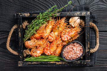Boiled  Greenland Prawn Shrimp in a wooden tray with herbs. Black wooden background. Top view