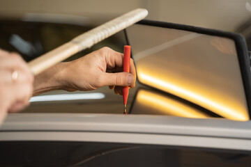 Process of Repairing Dents On Car Body. Technician Is Working Using Professional Tools For...