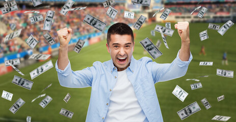 online betting, gambling and sport concept - happy man with raised hands and money rain over football field background