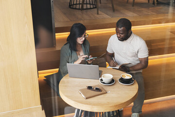 Portrait of two business people meeting at cafe table in graphic wooden interior, copy space