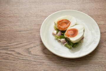 boiled spicy salty egg half cut with slice shallot and chili salad on plate