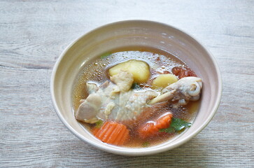 boiled chicken leg with potato soup on bowl