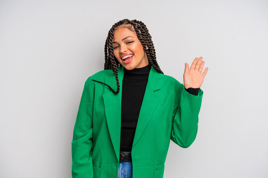 black afro woman smiling happily and cheerfully, waving hand, welcoming and greeting you, or saying goodbye