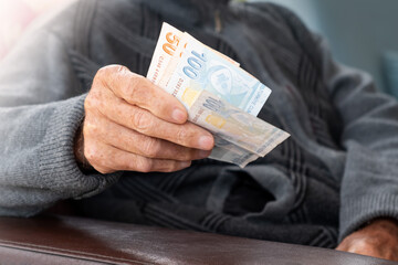 Senior man wrinkled hands holding Turkish Lira banknotes.Financial currency crisis concept.