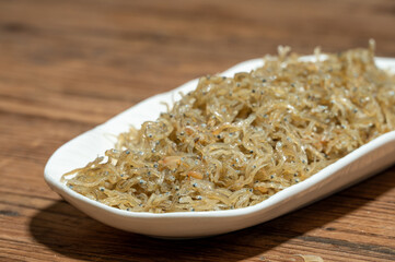 The dried clove fish in the container is on the wood grain table