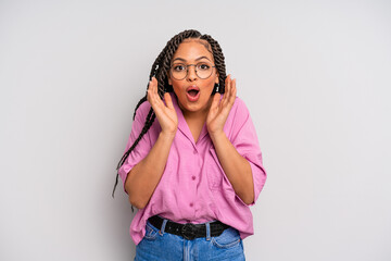 black afro woman feeling shocked and excited, laughing, amazed and happy because of an unexpected...