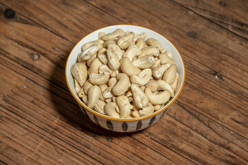Dried cashew nuts in containers on wooden countertops