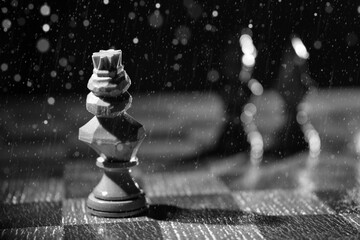 Chess piece of the king and blurred silhouettes in the distance, waiting. Black and white photo