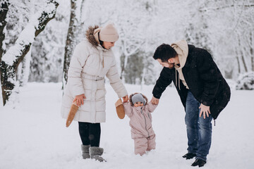 Fototapeta na wymiar Young family with little daughter in a winter forest full of snow