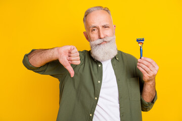 Photo of displeased mature man demonstrate razor show thumb down wear green shirt isolated yellow...