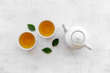 Obraz na płótnie Canvas Ceramic white teapot and black tea in two cups, top view