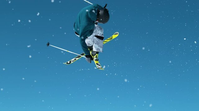 SLOW MOTION, CLOSE UP: Freestyle skier takes off a big kicker and does a spinning grab trick with crossed skis. Cinematic shot of a pro skier doing tricks on a sunny winter day in the Julian Alps.
