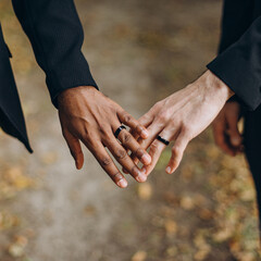 European Gay Couple holding hands, homosexual marriage wedding day. Gentle touch of a same sex couple - obrazy, fototapety, plakaty