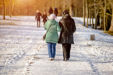 Two women walk along the path in the winter Park
