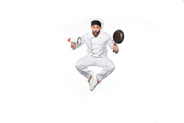 surprised chef in hat and uniform levitating while holding frying pan and megaphone isolated on...