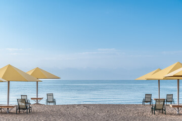 Seascape with sandy beach, umbrella and deck chairs. Design of summer vacation holiday