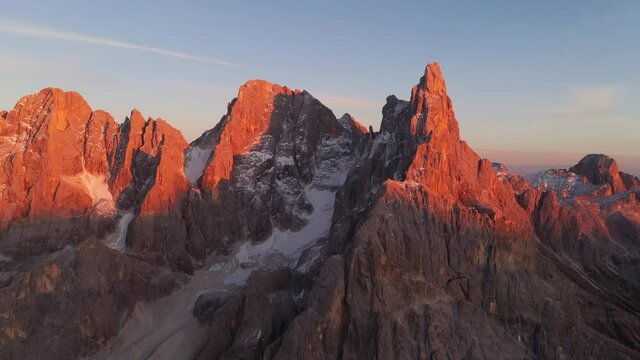 Aerial flight over the Pale di San Martino mountain group in sunset time. Hight mountains with glacier glowing by sunset light. San Martino di Castrozza, Dolomites, Trentino, Italy.