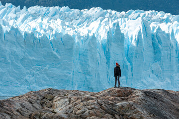 A woman standing on the rock formation next to the Perito Moreno Glacier and looking to the right