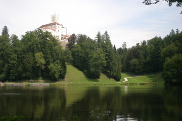 Fototapeta na wymiar A castle on the hills, decidous forest and a beautiful lake in summer
