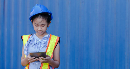 Asian little girl dress up engineering suit wearing helmet using tablet, engineering foreman and...