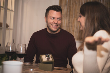 a girl gives a watch to her boyfriend in the middle of a meal in a restaurant.Valentine's, birthday.