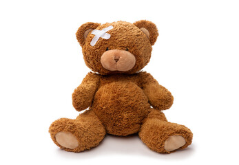 medicine, healthcare and childhood concept - teddy bear toy with medical patch on head on white...