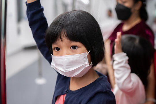 Little girl with surgical mask face protection flu and Virus outbreak in public transportation (skytrain or subway). Concept of New normal lifestyle, Using public transport to travel to school.