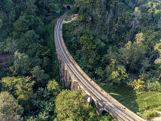 Fototapeta na wymiar Sri Lanka. The attraction is the ancient railway Nine-arch Demodara Bridge in the midst of a dense tropical forest. Shooting from the air on a drone. Sunny day, sunset.