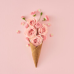 Creative blooming composition. Pink flowers and ice cream cone on pastel pink background, flat lay....