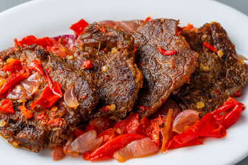 Jerado balado or Dendeng balado is a traditional cuisine from west sumatera, indonesia. it is made from slice of beef with spicy sauce called sambal. served on plate and isolated gray background