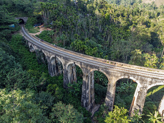 Fototapeta na wymiar Sri Lanka. The attraction is the ancient railway Nine-arch Demodara Bridge in the midst of a dense tropical forest. Shooting from the air on a drone. Sunny day, sunset.