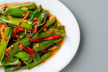 tumis genjer or oseng genjer is Indonesian traditional food. Served on white plate and isolated on gray background.