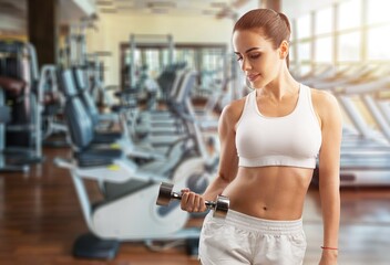 Workout in gym by a beautiful woman using dumbbell. Sport woman warm up before a workout.