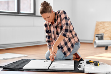 repair, improvement and furniture concept - woman with screwdriver assembling locker at home