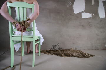 Young girl tied up on the floor. The abducted girl. The victim of violence sits on the floor with...