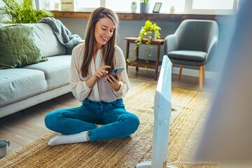 Woman checking with device radiators in living room of smart home, IOT . Young woman with heating...