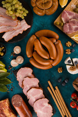 Sausages, bacon and meat delicacies. Sliced meat, ham with olives, grapes, breadsticks, brie...