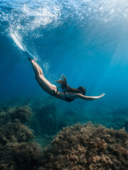 Freediver woman with fins dive underwater in crystal ocean.