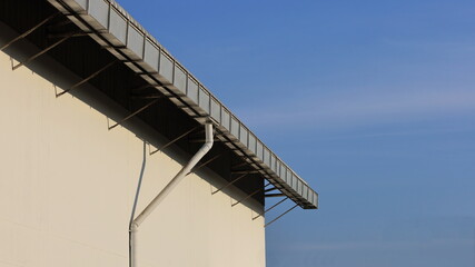 Fototapeta premium Drain on the roof. Rain gutter made with zinc installed as a long line on the roof. On the blue sky background with copying area. Selective Focus
