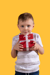 Portrait of happy cute little boy holding box of birthday present, smiling excitedly at camera. Celebration and childhood