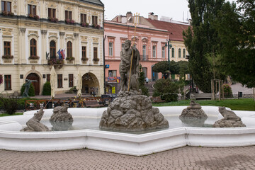 Old building in town with decorative milling cutters. View of the fountain with stone Neptune and other monsters. - obrazy, fototapety, plakaty