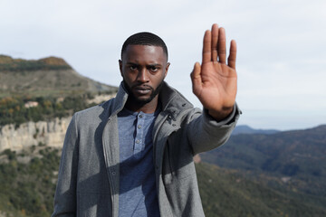 Naklejka premium Man with black skin gesturing stop in winter in nature
