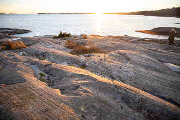 People walking on a rocky shore in Bjorno nature reserve at Baltic sea. Beautiful natural Scandinavian landscape on Sunny late autumn or winter day in Sweden, Stockholm archipelago 2021.12.17